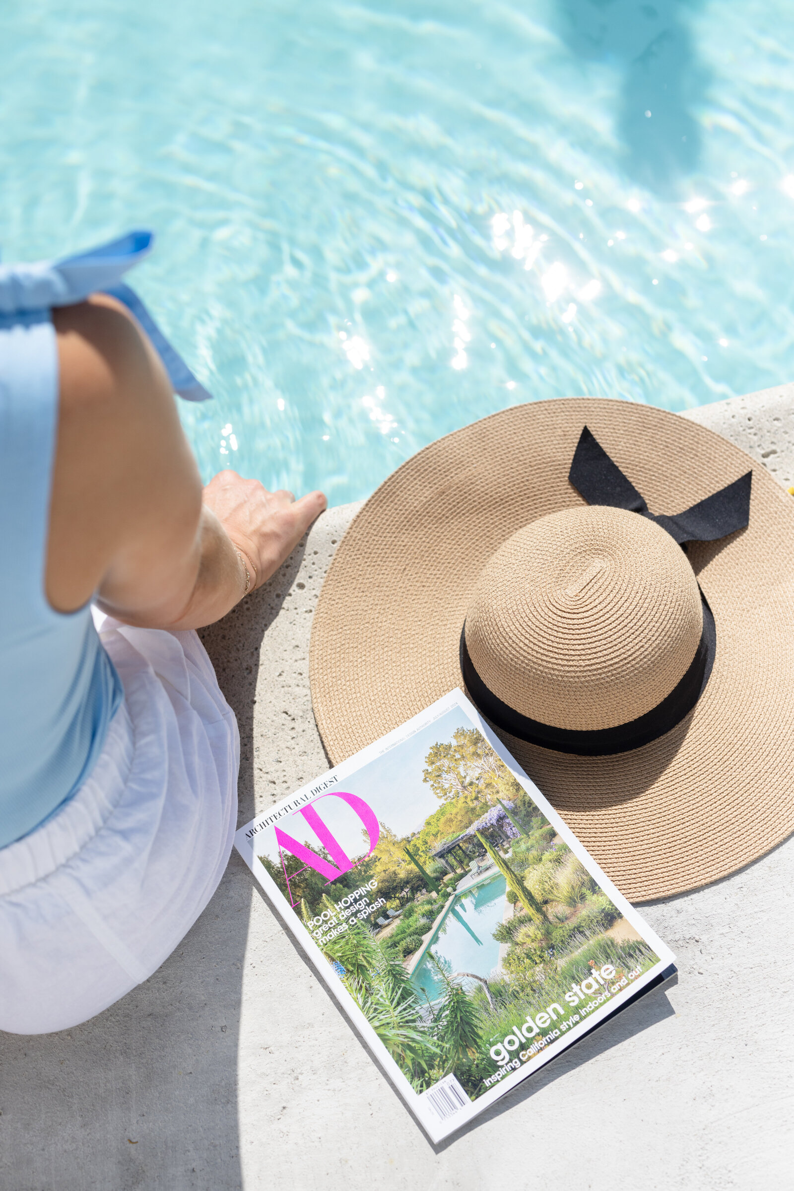 A drink, notebook, and hat beside the pool at an event